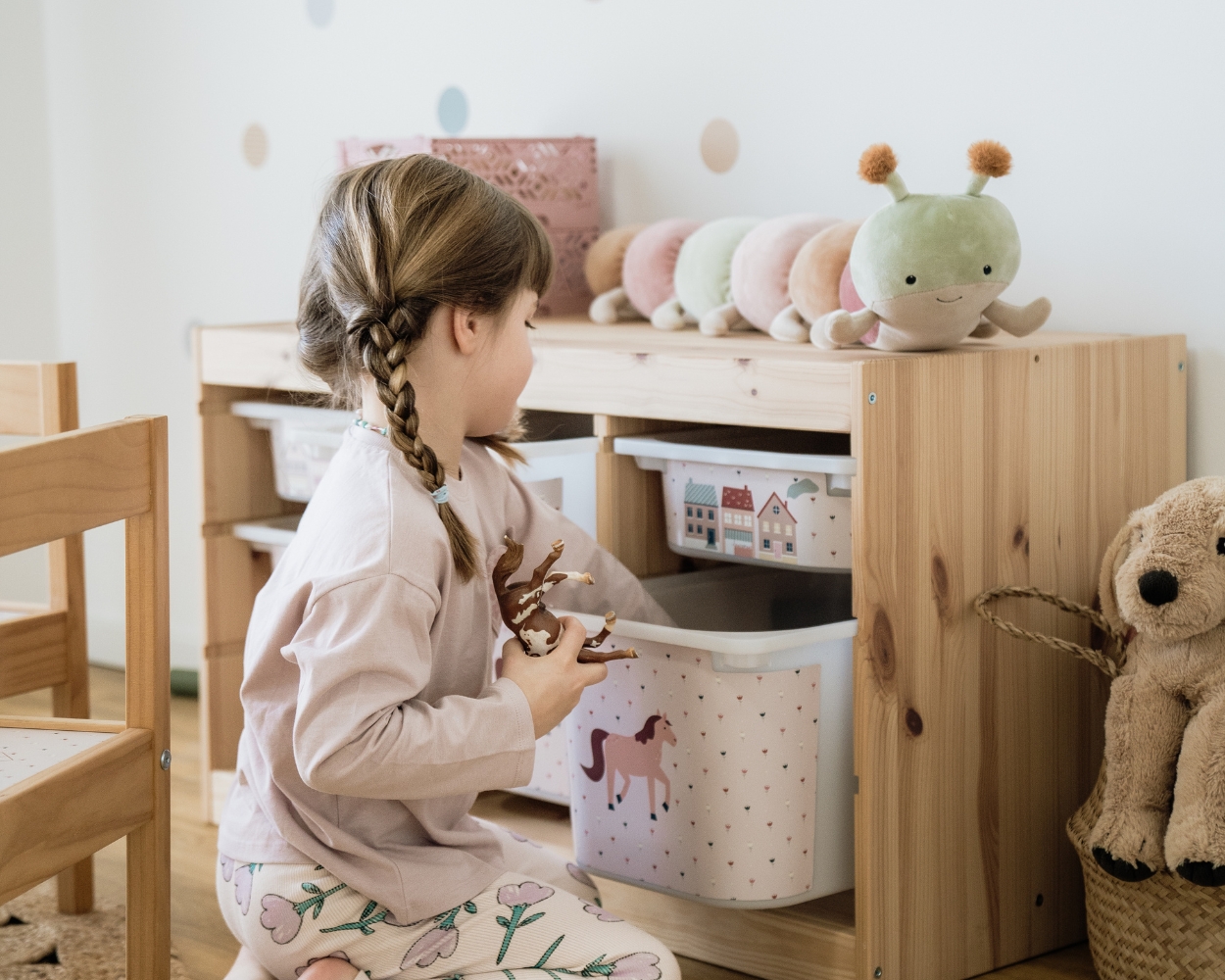 Kinderzimmer Tiere mit Tiermotiven Ein Mädchen spielt in seinem Kinderzimmer Tiere und greift in das Ikea Trofast Regal, welches mit Limmaland Klebefolien mit Pferde Motiven gestaltet wurde
