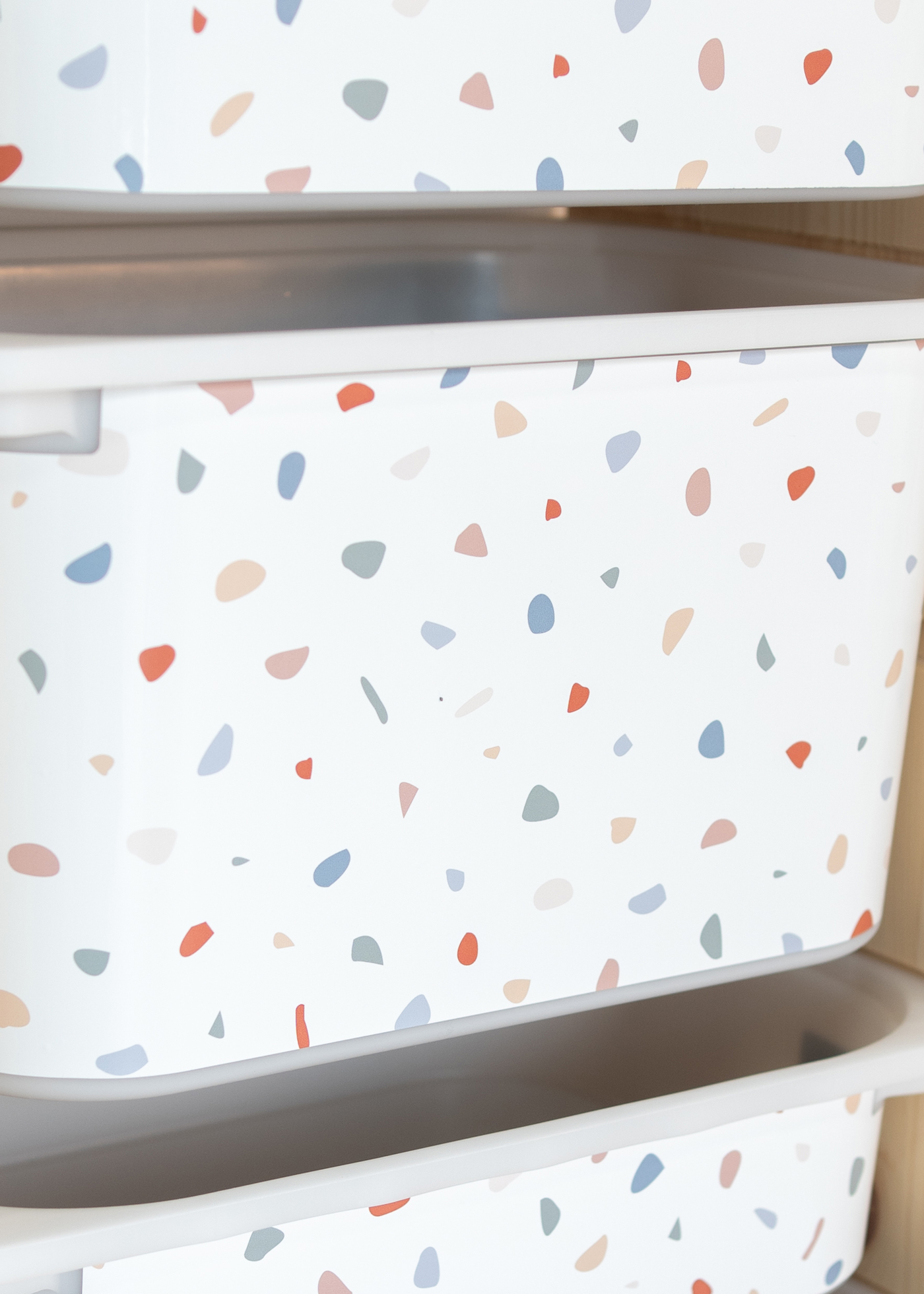 TROFAST Regal mit Aufbewahrungsbox und buntem Terrazzo-Muster Aufbewahrungsbox im IKEA TROFAST Regal, dekoriert mit einer Klebefolie im bunten Terrazzo-Design.