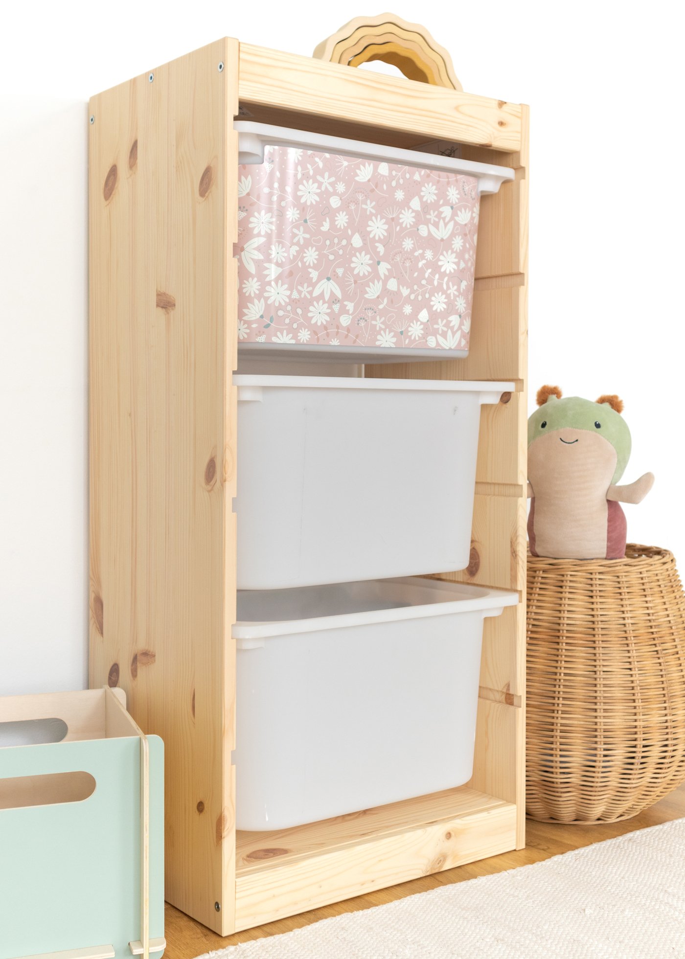 Aufbewahrungsbox im IKEA TROFAST Regal mit einem weichen rosa Blumenmuster, ideal für Kinderzimmer.