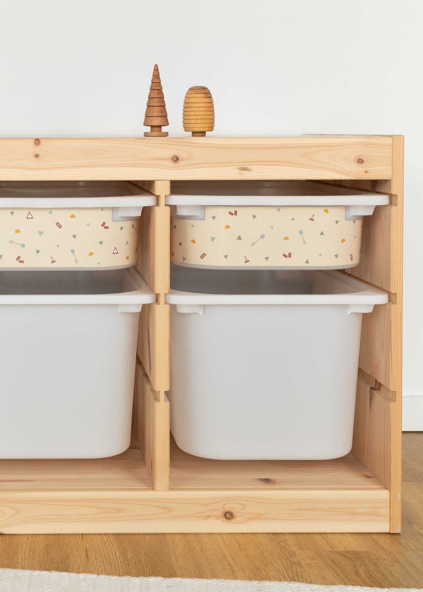 Kinder-Aufbewahrungsbox mit Baustellen-Design im IKEA Regal Kleine beige Aufbewahrungsbox im IKEA TROFAST Regal mit Baustellen-Motiven, darunter eine große weiße Box zur zusätzlichen Aufbewahrung.