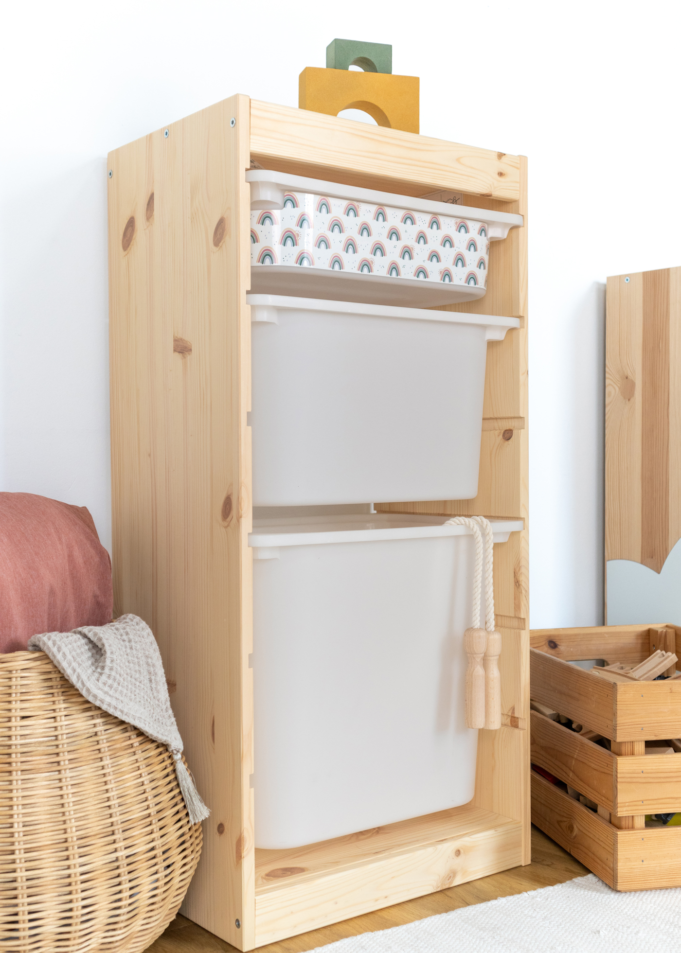 Aufbewahrungsbox mit Regenbogen-Muster im IKEA Regal Kinderfreundliche Box mit einem wiederkehrenden Regenbogen-Motiv im IKEA TROFAST Regal.