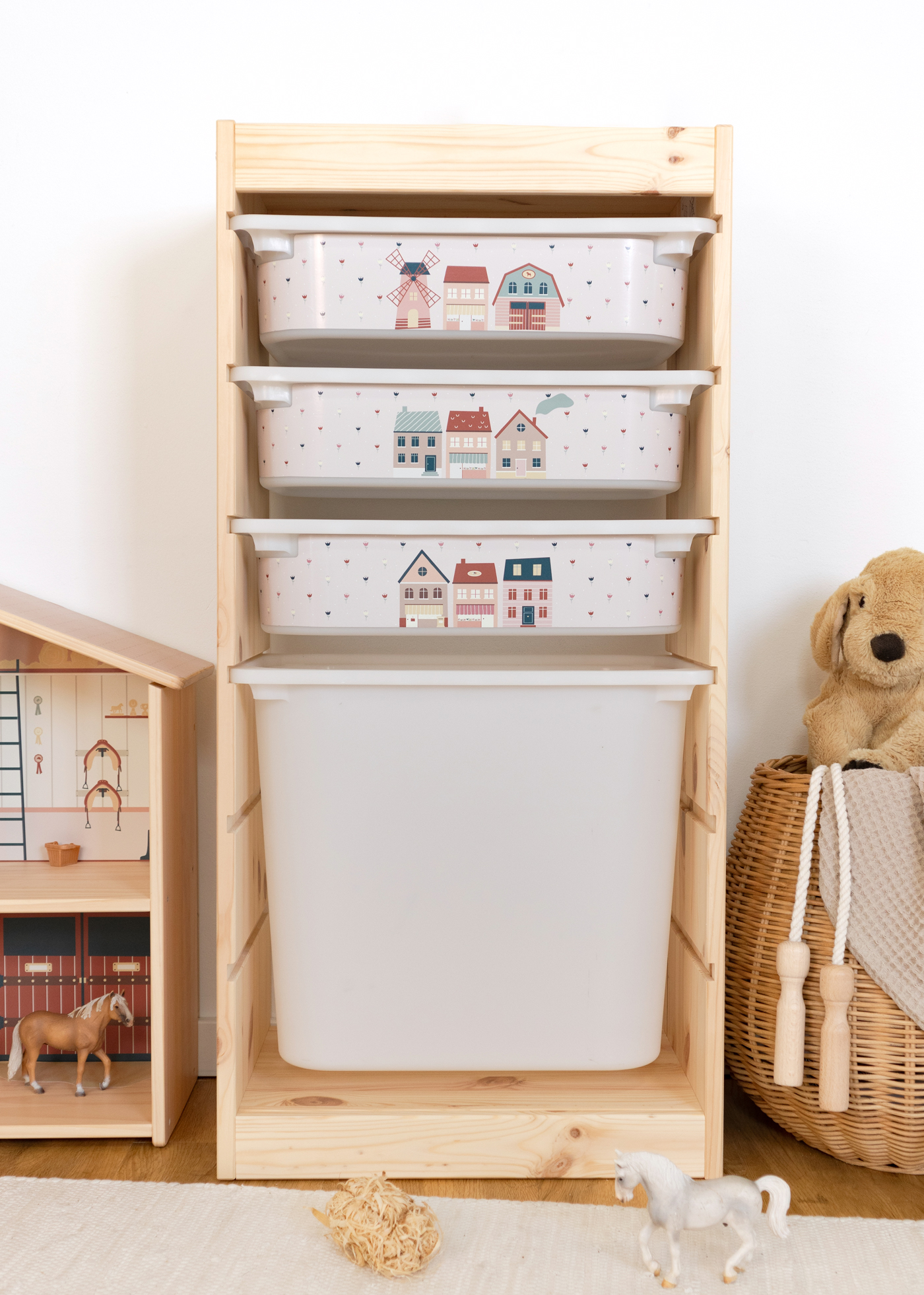 TROFAST Regal mit rosa Aufbewahrungsbox und Dorf-Motiv Rosa Aufbewahrungsbox im IKEA TROFAST Regal, dekoriert mit einem kindgerechten Dorf-Motiv.